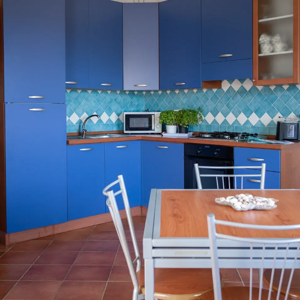 Cucina con mobili blu, piastrelle azzurre a rombi e tavolo da pranzo